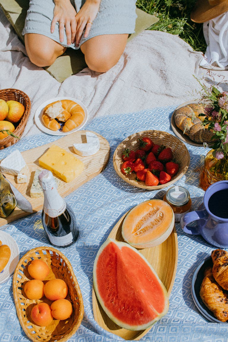 A cozy picnic featuring fresh fruits, cheese, and wine on a sunny day.