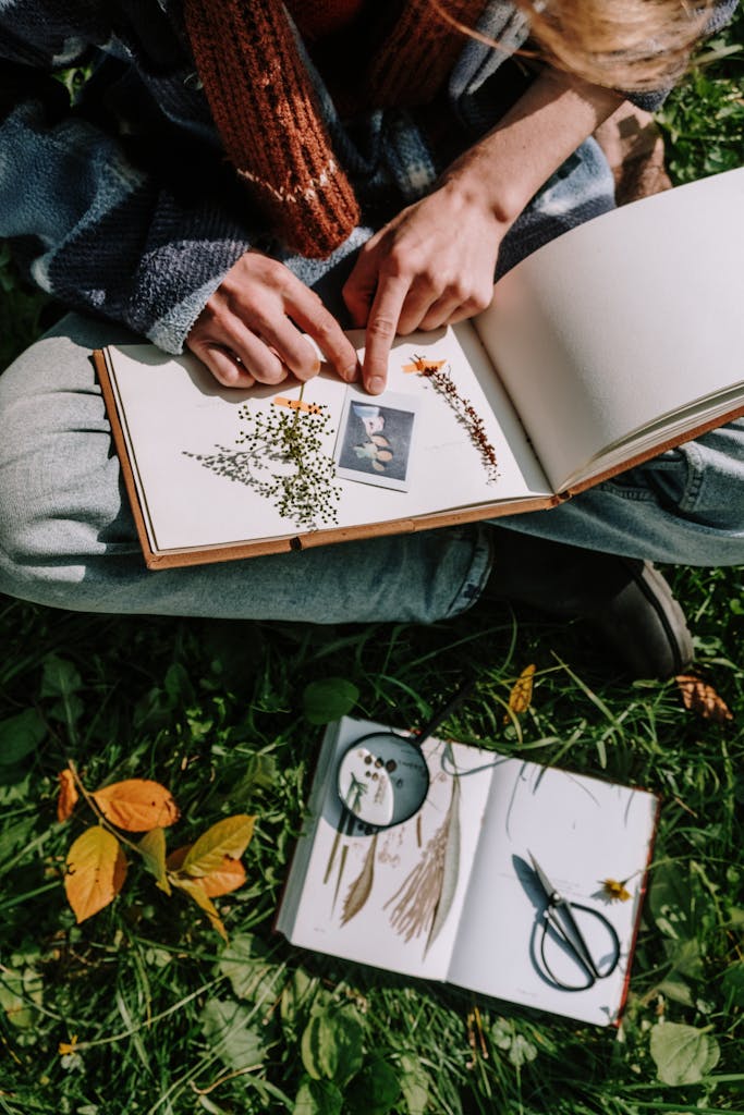 Person engages in outdoor scrapbooking with dried flowers, emphasizing creative hobbies and nature. green witch journal...