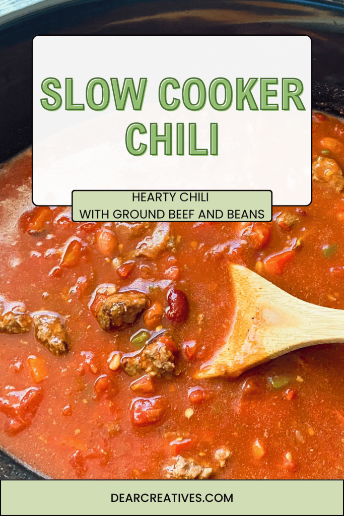 Slow Cooker Chili in a slow cooker with a wood spoon with chili sauce, beans, and ground beef and herbs.