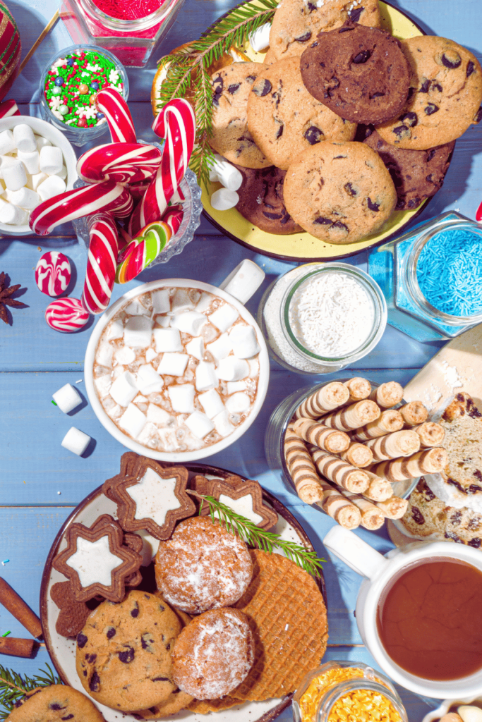 hot cocoa bar filled with toppings, cookies, candy canes, marshmallows, festive cookies and favorite winter cookies on plates.