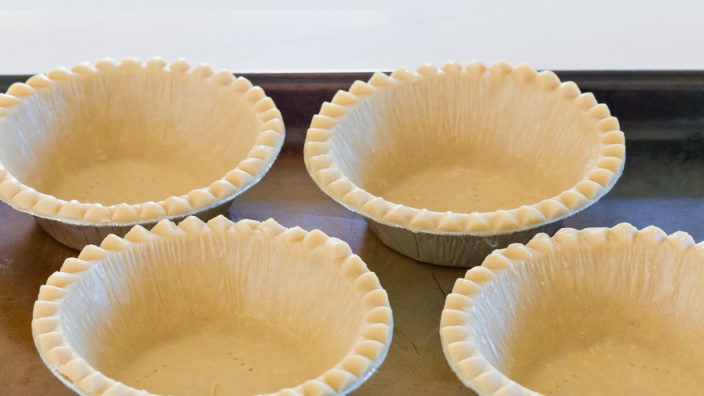 Unbaked pastry shells pricked with a fork on a baking sheet ready to blind bake for beef pot pie.