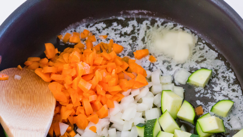 Vegetables sautéing in a pan with butter and oil as the first step for homemade beef pot pie filling.