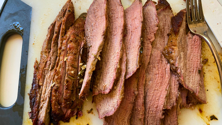 closeup image of Sliced cast iron tri-tip on a cutting board showing juicy, tender beef with a flavorful crust .png