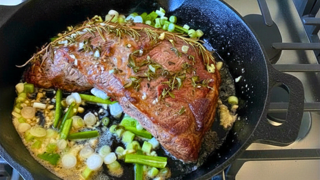Finished cast iron tri-tip resting in skillet after oven cooking, juicy and tender and ready to slice.