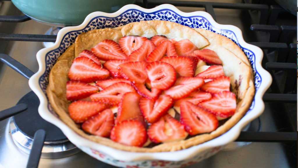 photo of layers of sliced fruit, sliced strawberries and bananas being adding to a pastry pie shell with chocolate. Next a layer of vanilla pudding with cream cheese will get layered on top, then chill for an easy dessert