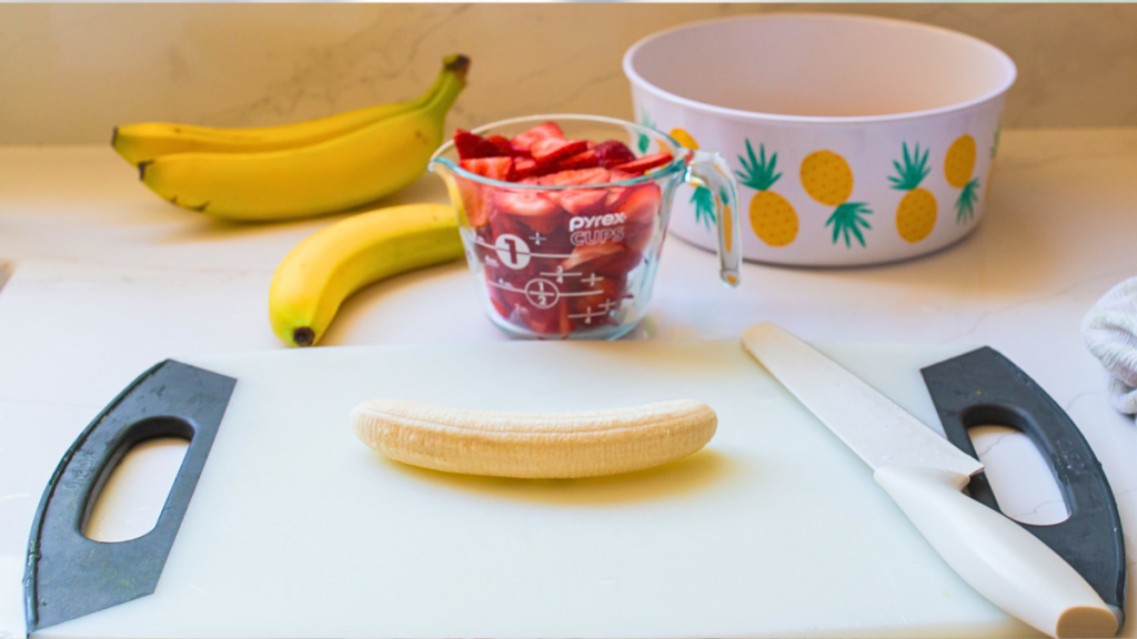 slicing fruit for a pie, bananas, strawberries, and crushed pineapple draining in a bowl. Preparing a banana strawberry fruit pie banana split pie