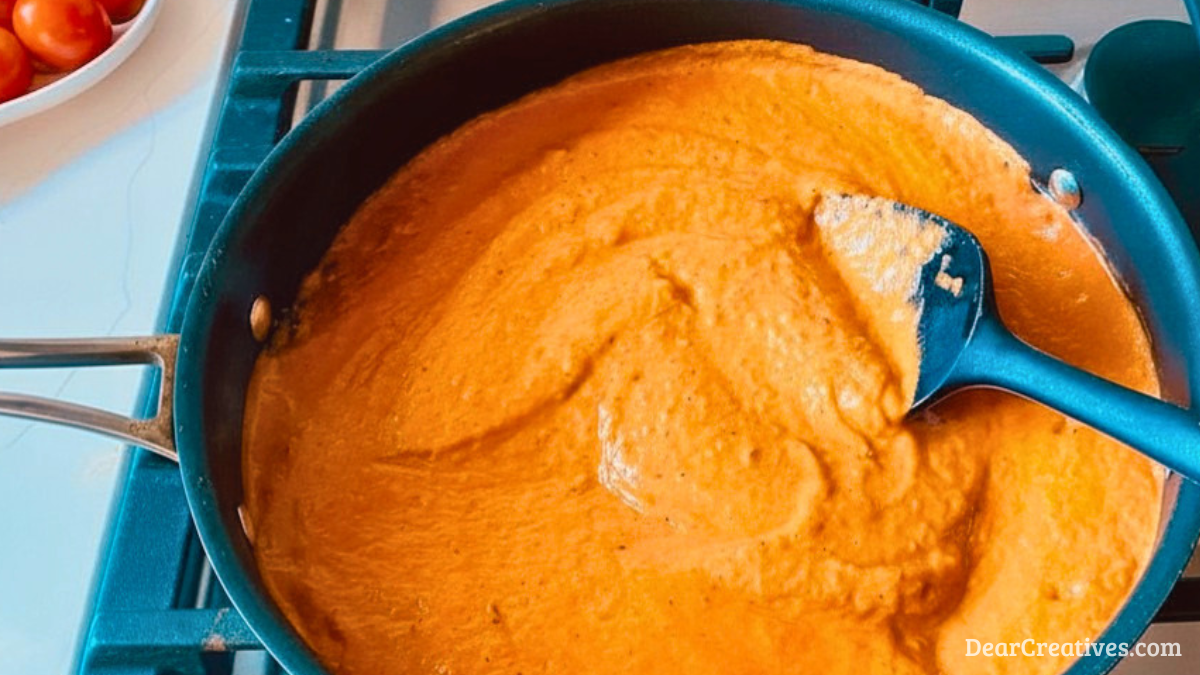 Close up of finished tomato sauce in the pan with a spoon, ladle, or heat safe spatula ready for adjusting thickness .png