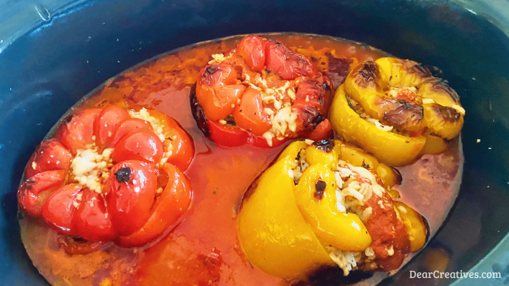 Slow cooker stuffed bell peppers with ground beef, rice, zucchini, tomatoes, and Parmesan cheese, cooked in marinara sauce and ready to serve.