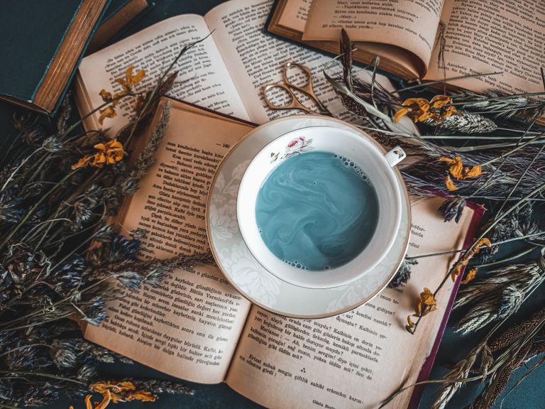 Vintage books, dried botanicals, and a potion-like cup of tea set a cozy, magical mood.