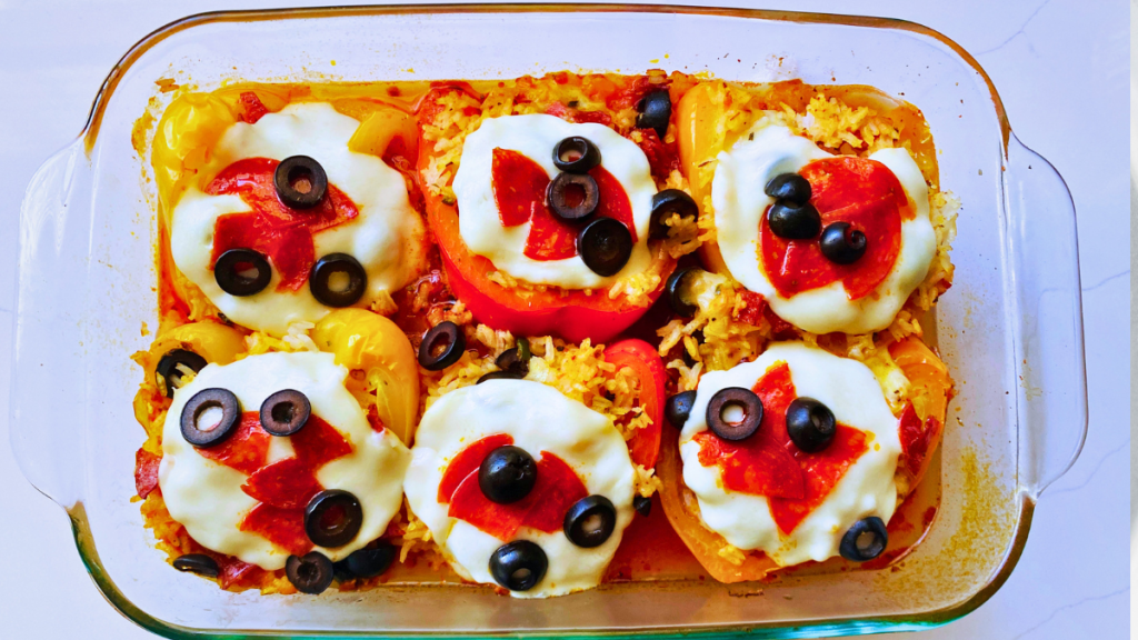 Pizza stuffed bell peppers filled with rice and topped with melted mozzarella, pepperoni, and black olives in a baking dish.