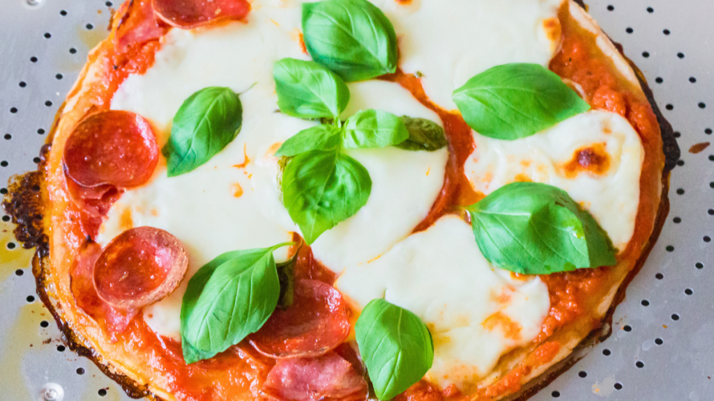 Freshly baked pepperoni and Italian salami pizza with melted mozzarella and basil before slicing.