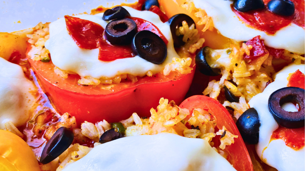 closeup of pizza stuffed peppers with melted mozzarella cheese, pepperoni, black olives, rice mixture and Don Pepinos pizza sauce
