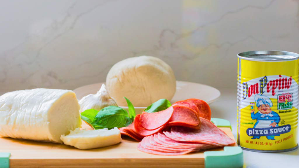 Ingredients for easy pepperoni pizza, including pizza dough, Don Pepino Pizza Sauce, fresh mozzarella, pepperoni, Italian salami, and fresh basil.